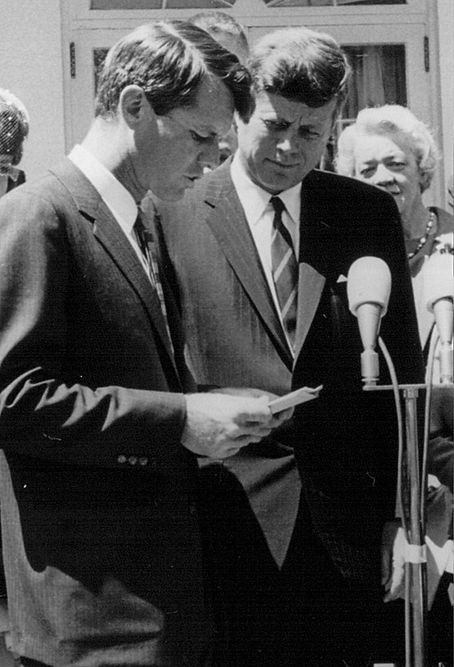 President John F. Kennedy listens as his brother Robert Kennedy speak at a White House ceremony May 7, 1963.